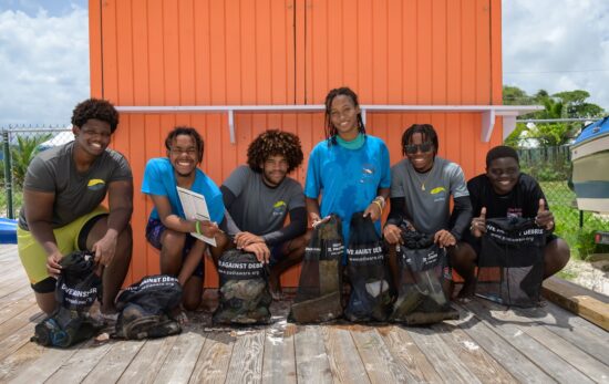 a bunch of people pose after cleaning trash out of the ocean