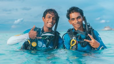 two divers pose and smile for the camera on the surface of the water
