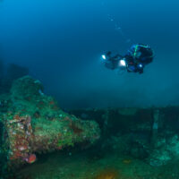 Scuba diver exploring and taking pictures of an underwater wreck