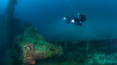Scuba diver exploring and taking pictures of an underwater wreck