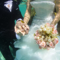 A bride and groom are photographed underwater