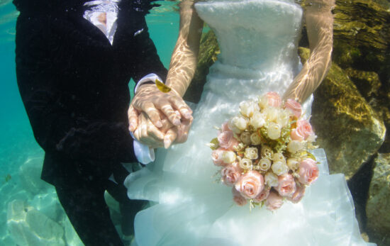 A bride and groom are photographed underwater