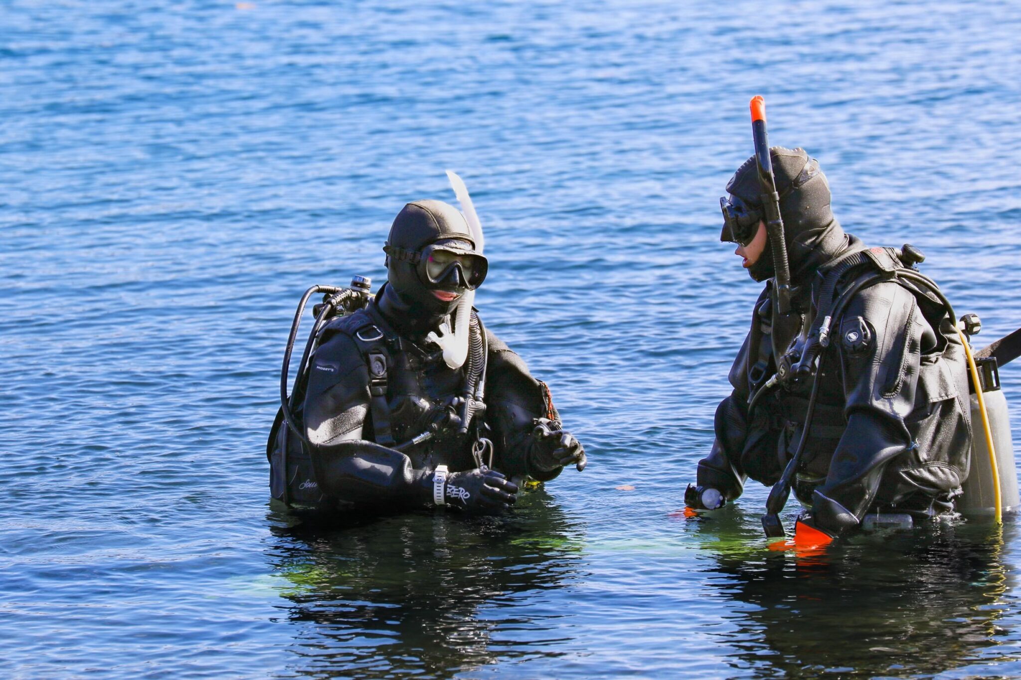 Instructor and student divers are in the water up to their waists, doing the training.