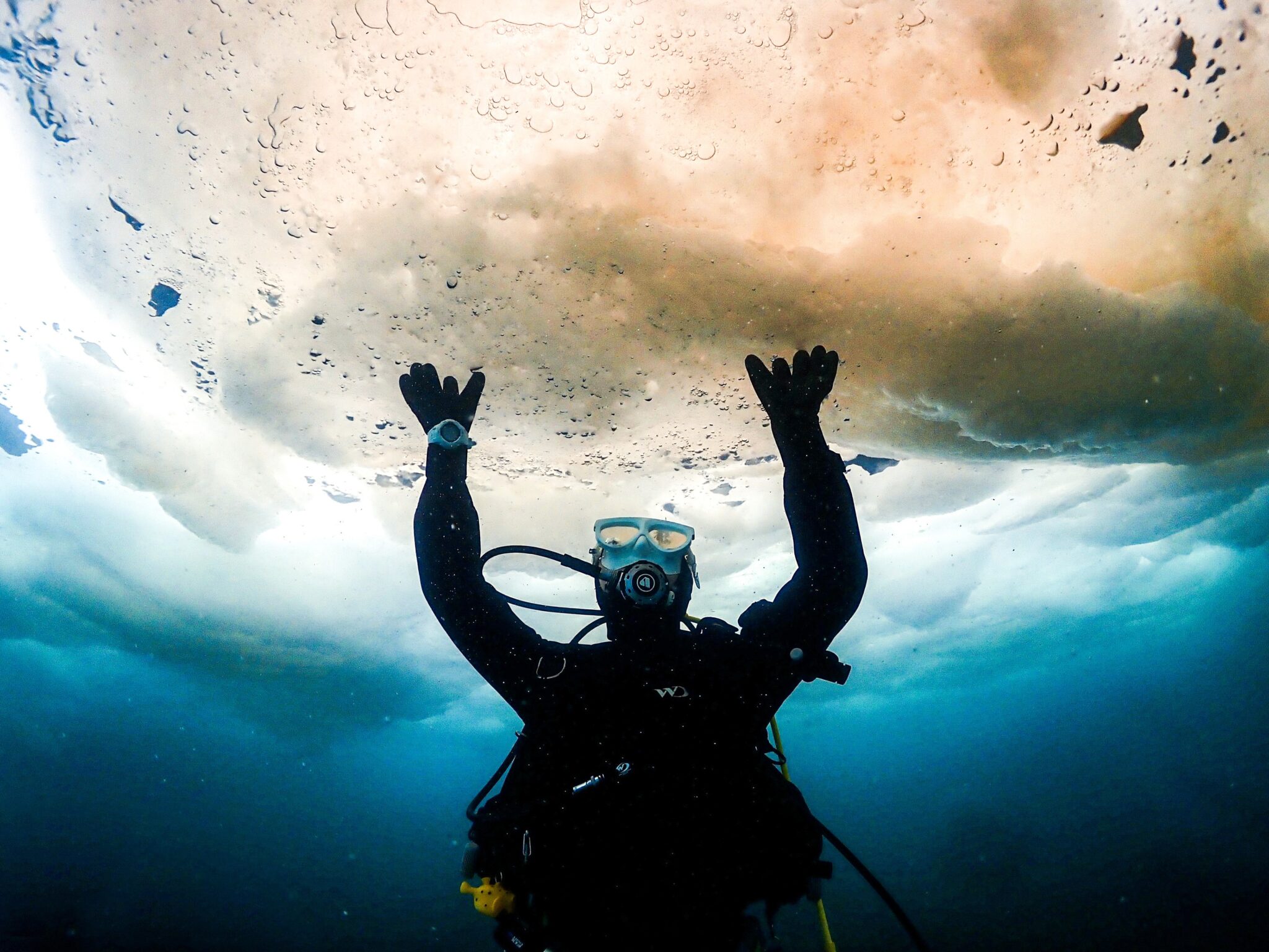 A diver dives under drift ice and makes it look like it is supporting the drift ice.