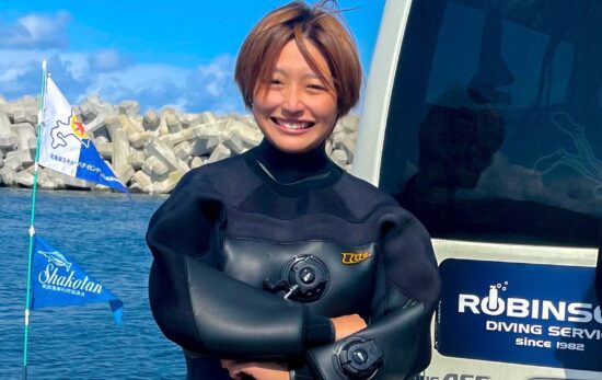 Short haired woman in dry suit posing professionally with arms crossed.