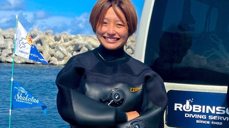 Short haired woman in dry suit posing professionally with arms crossed.