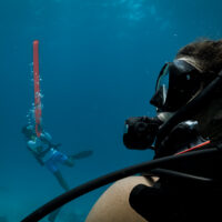 a diver watches another diver deploy an SMB