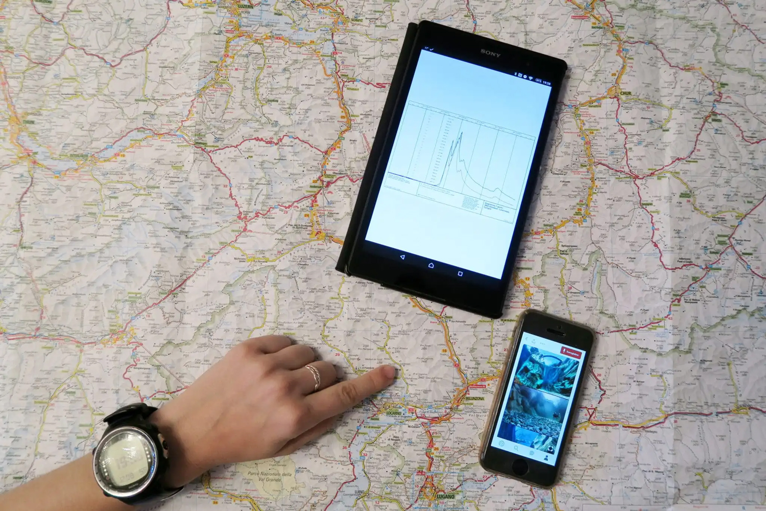 A diver wearing a dive computer uses a map, tablet, and mobile app to plan a dive that follows diving rules and regulations