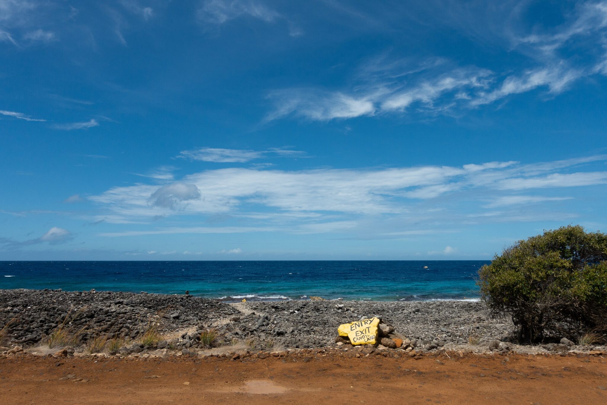 A yellow rock on the side of the road marks the entry and exit point for a dive site in Bonaire