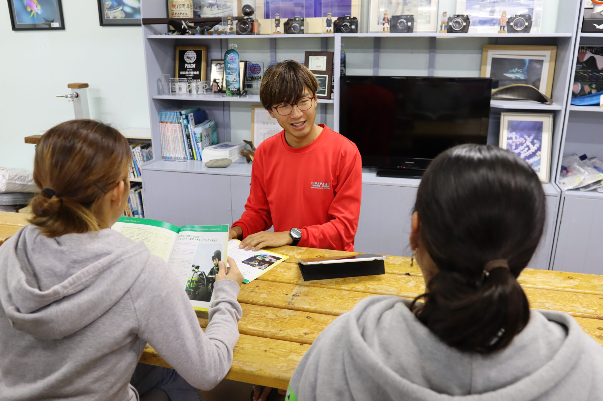 An Instructor lecturing to two student divers around a table.