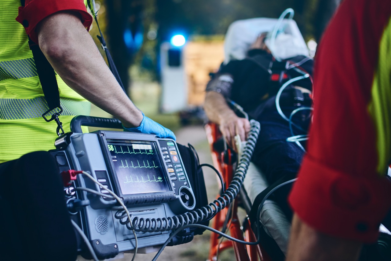 Team of emergency medical service rescuing old patient. Selective focus on heart rate monitor.