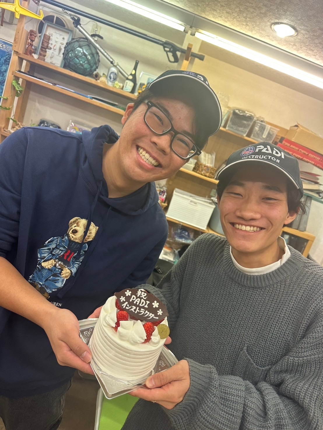 Two young men, newly certified instructors, celebrate their certification with a cake.