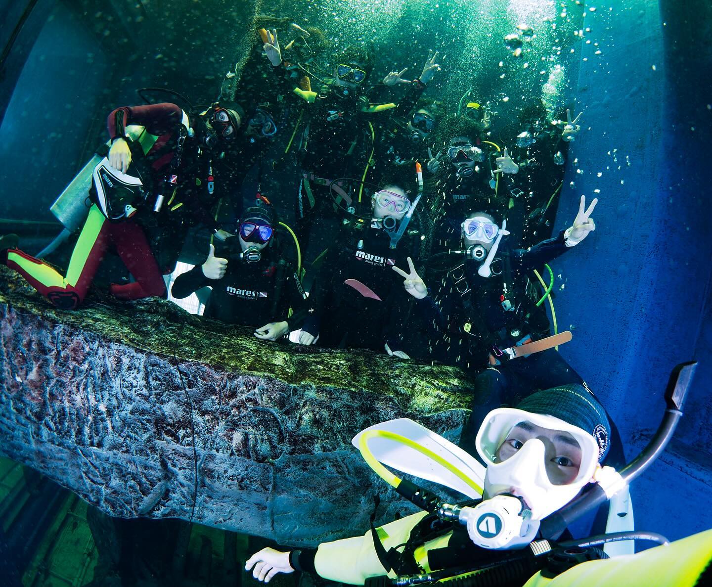 Underwater selfie of a large group of student divers enjoying a dive in a large aquarium