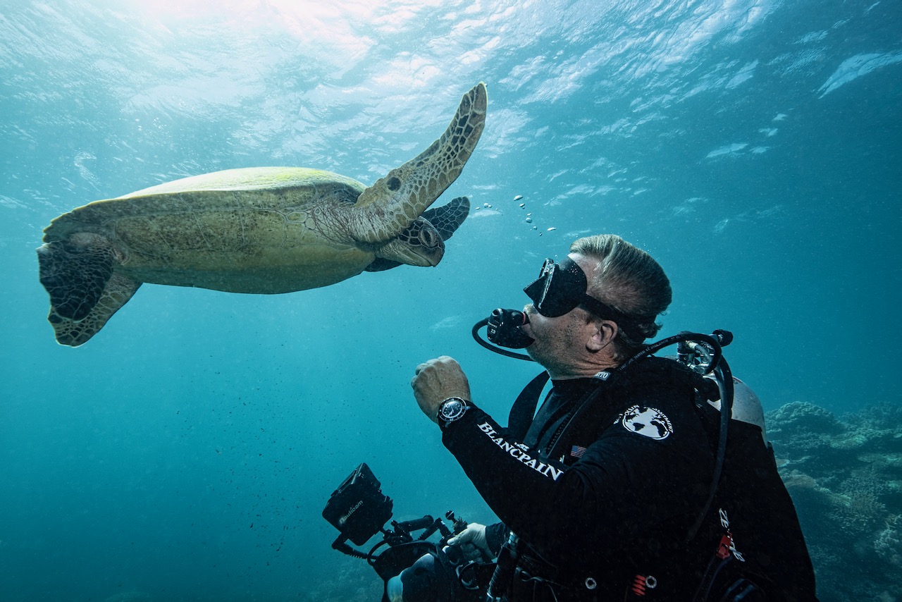 PADI CEO Drew Richardson scuba diving with a turtle