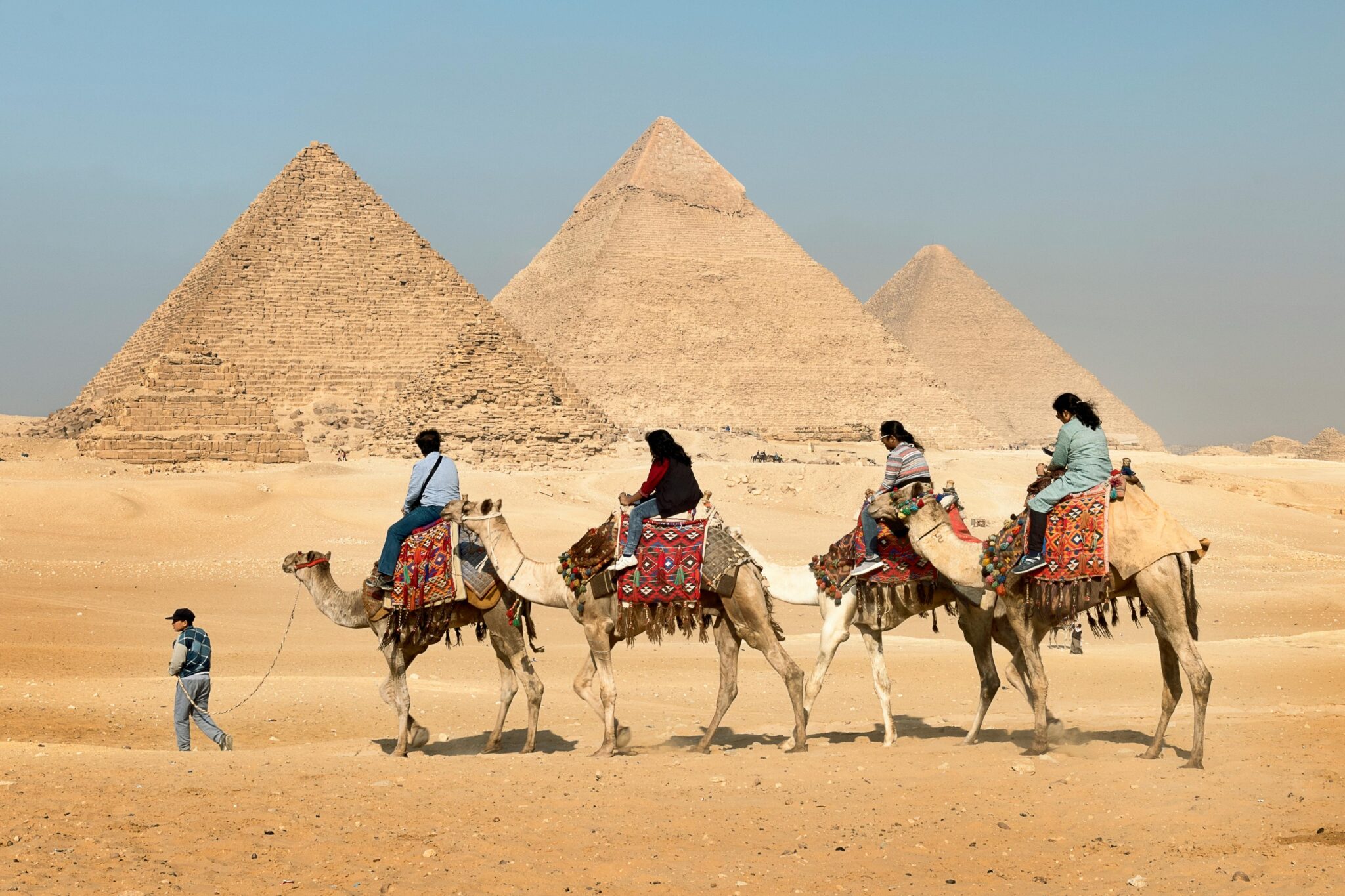 The Pyramids of Giza in Egypt Tourists ride camels in the desert in front of three pyramids at Giza in Egypt where you can mix diving with ancient wonders