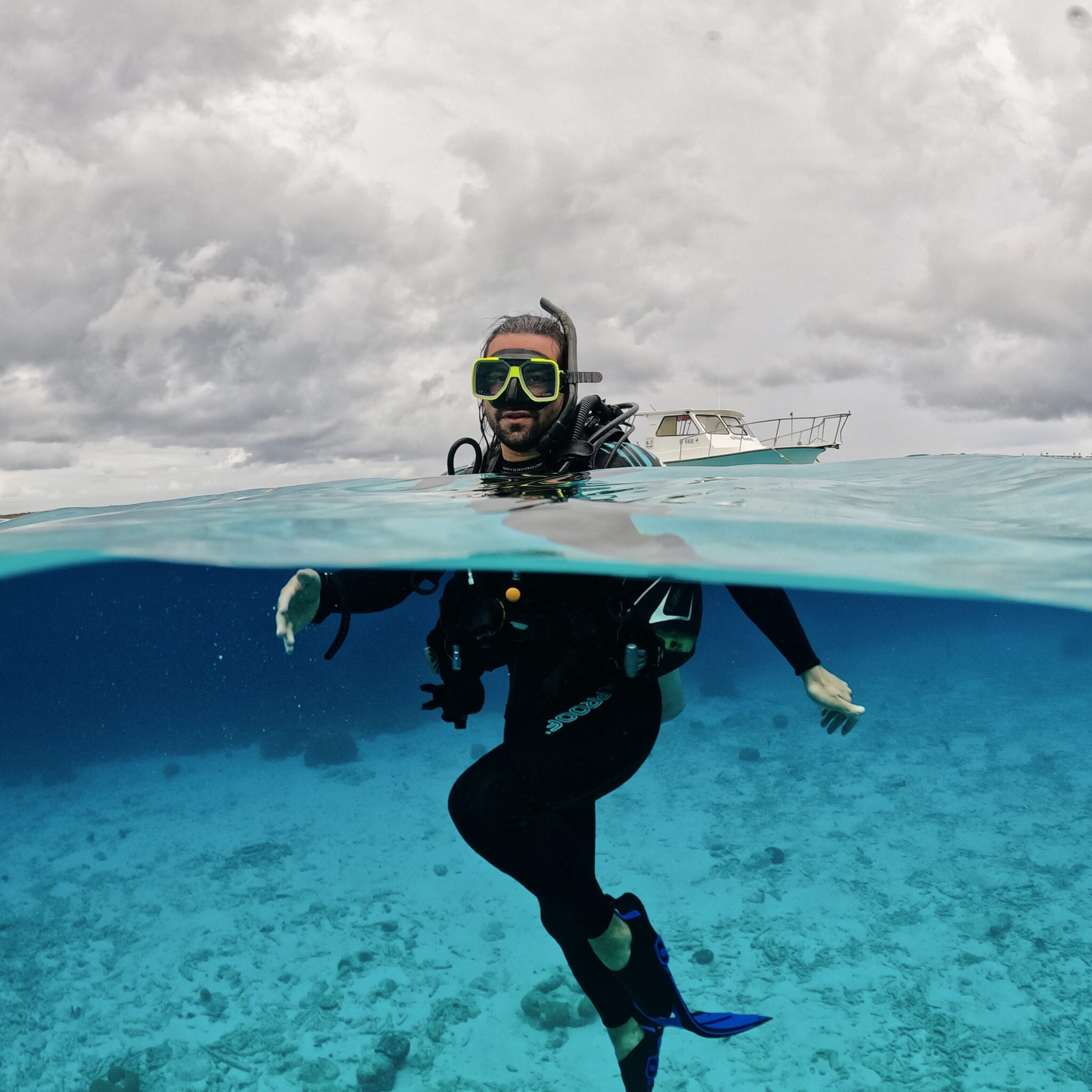 James Barrett surfaces after a scuba dive with a boat in the background.