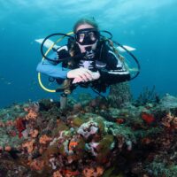 A diver wearing a skeleton rash guard floats facing the camera with her hands folded in front of her