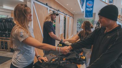 Two PADI Dive Center staff shaking hands with customers who are about to start a new course