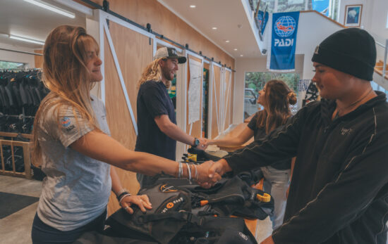 Two PADI Dive Center staff shaking hands with customers who are about to start a new course