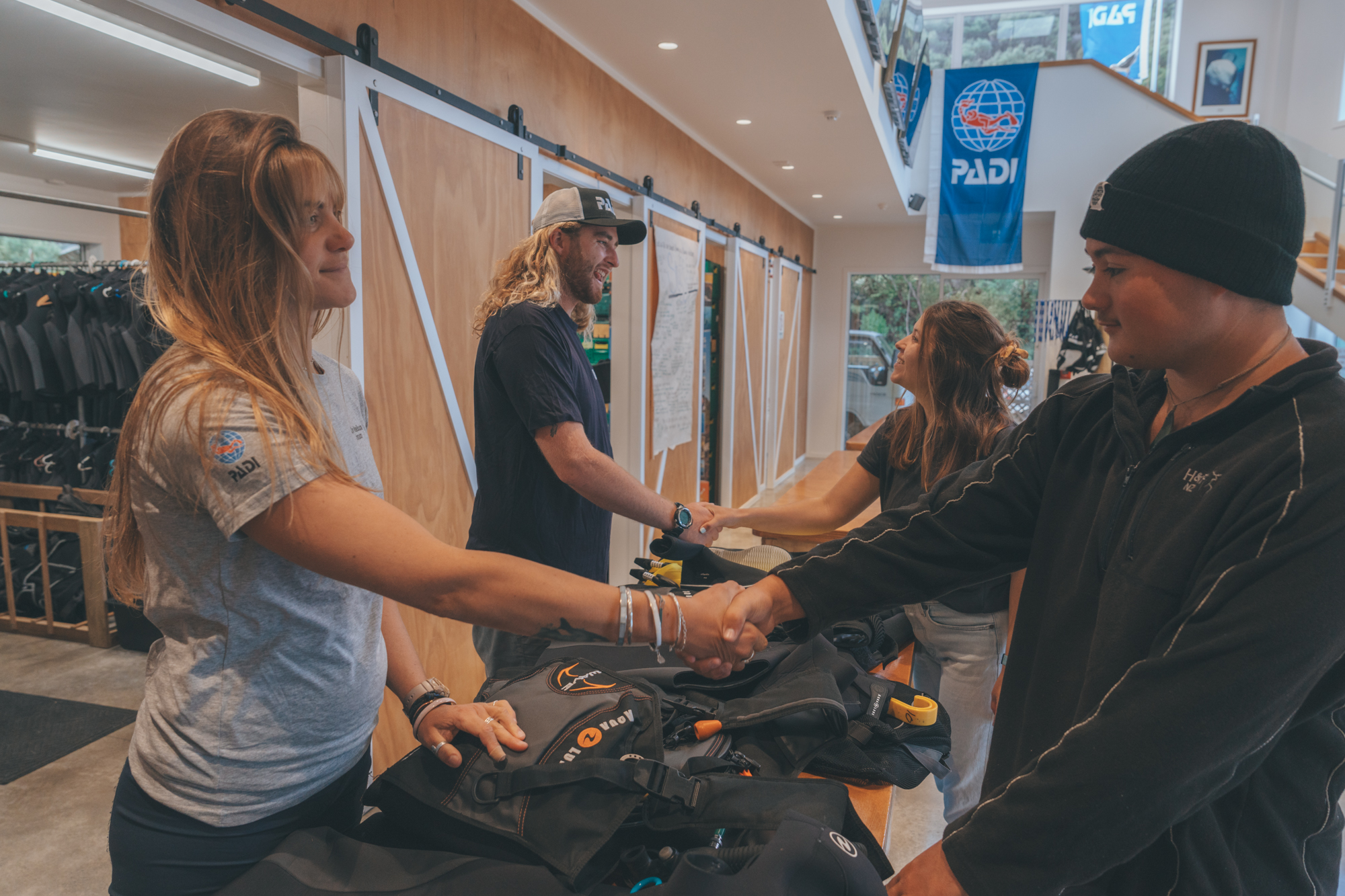 Two PADI Dive Center staff shaking hands with customers who are about to start a new course