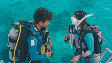 A scuba buddy pair completing pre-dive checks on the boat before their dive