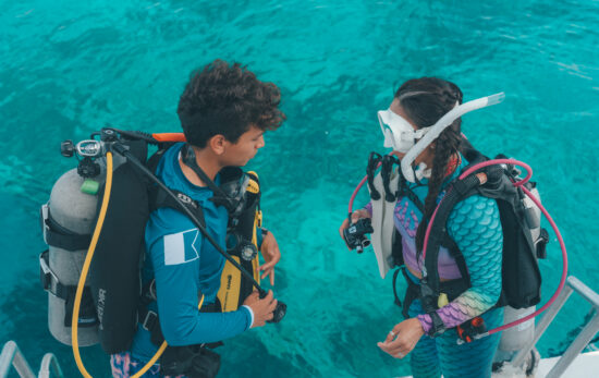 A scuba buddy pair completing pre-dive checks on the boat before their dive