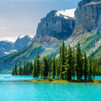 A lake in Canada with large cliffs looming above and a tree covered island in the middle