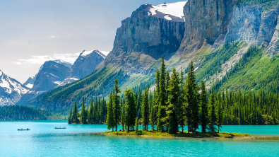 A lake in Canada with large cliffs looming above and a tree covered island in the middle