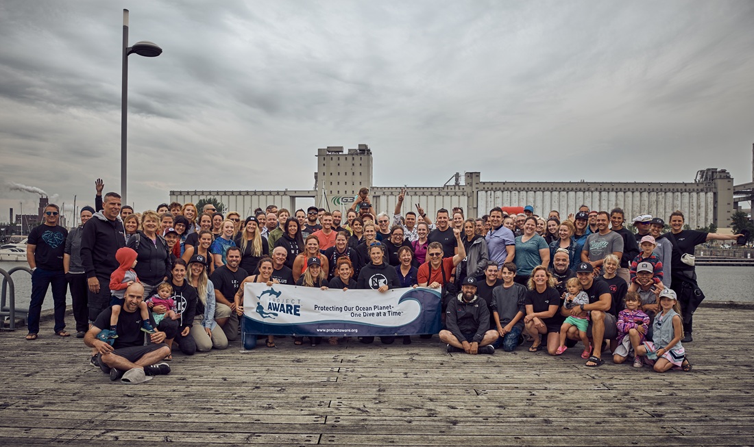 A large group of cleanup volunteers holding a PADI AWARE banner