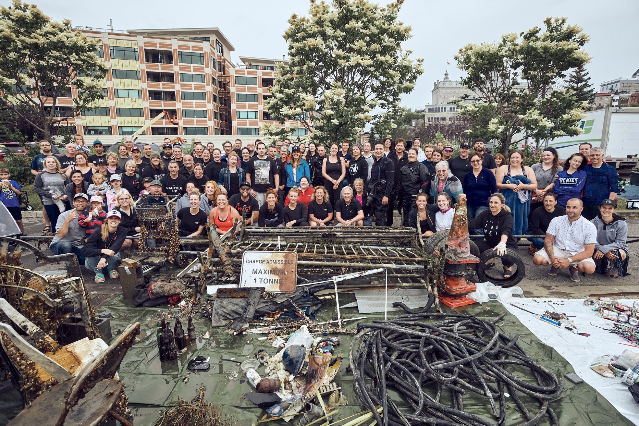 한 무리의 정화 자원봉사자들이 해양 쓰레기 더미 뒤에 서 있습니다.