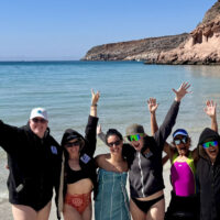 Divers waving on the beach on the LGBTQIA+ Baja Dive Expedition to promote diversity in scuba diving