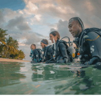 four divers walking out of the ocean