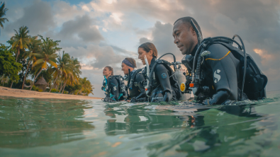 four divers walking out of the ocean
