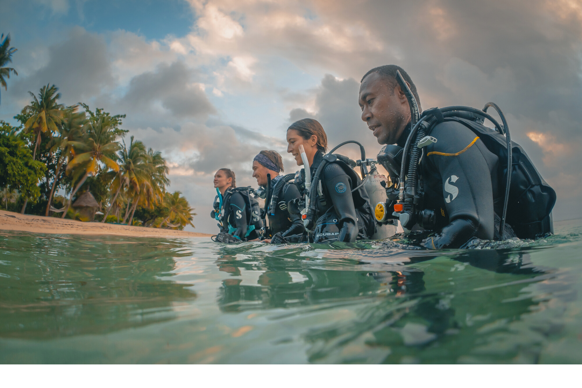 four divers walking out of the ocean