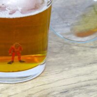 A miniature scuba diver figurine in the bottom of a beer glass