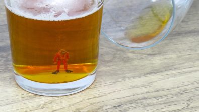 A miniature scuba diver figurine in the bottom of a beer glass