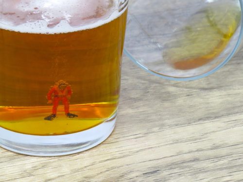 A miniature scuba diver figurine in the bottom of a beer glass