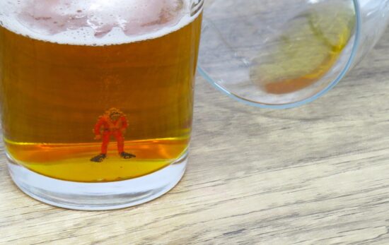 A miniature scuba diver figurine in the bottom of a beer glass
