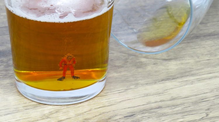 A miniature scuba diver figurine in the bottom of a beer glass