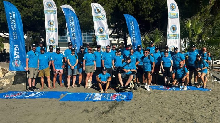 Group of divers on the beach for the Diving for Peace event in Cyprus 2026 all wearing PADI tshirts with PADI banners