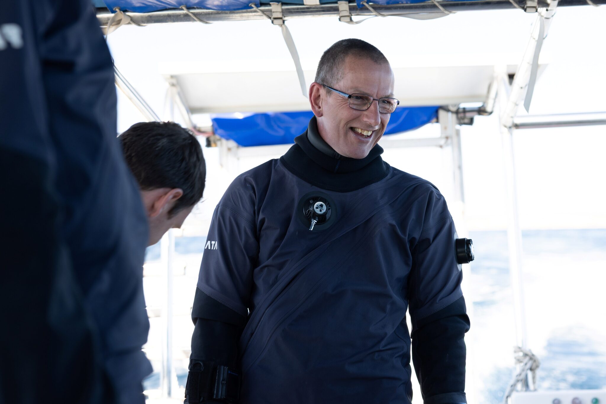 Photo of Phil Short, part of the DEEP team, on a boat talking to other team members
