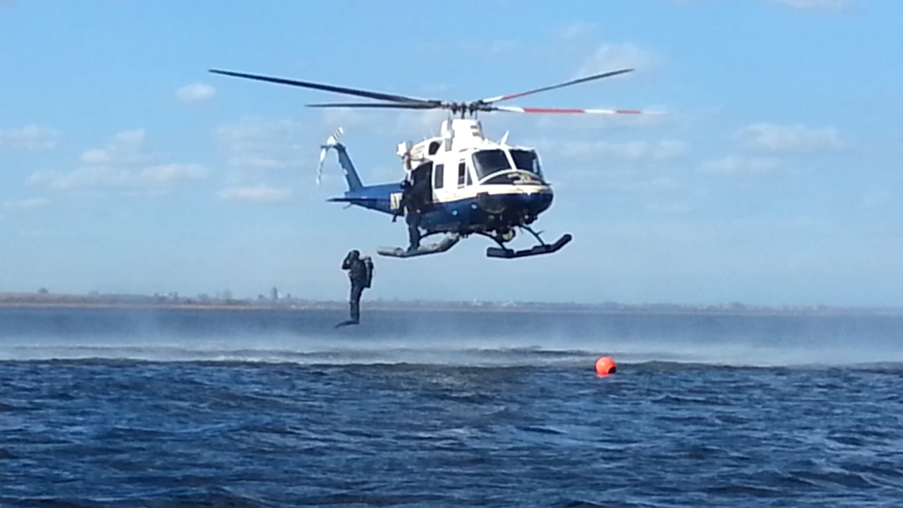 An NYPD Scuba Team member jumps out of a helicopter