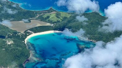 An aerial view of Culebra Island (Isla Culebra) in Puerto Rico. A blue bay and green slopes can be seen beneath a smattering of white cloud.