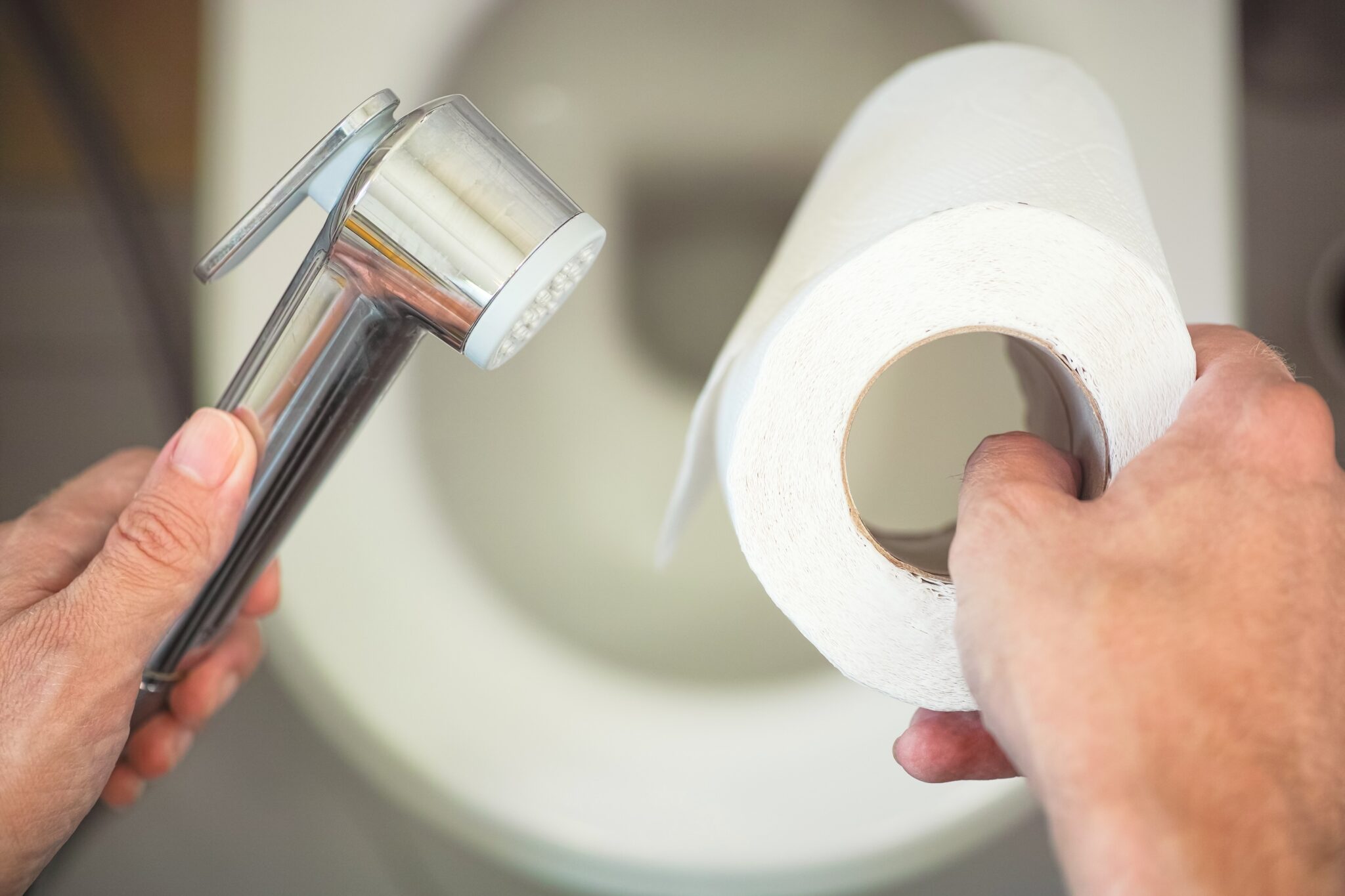 Bidet shower and toilet paper. Close up.
