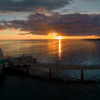 Aerial shot of a diving bell at the end of a pier at sunrise golden hour revealing the rising sun in the Baltic sea, Germany