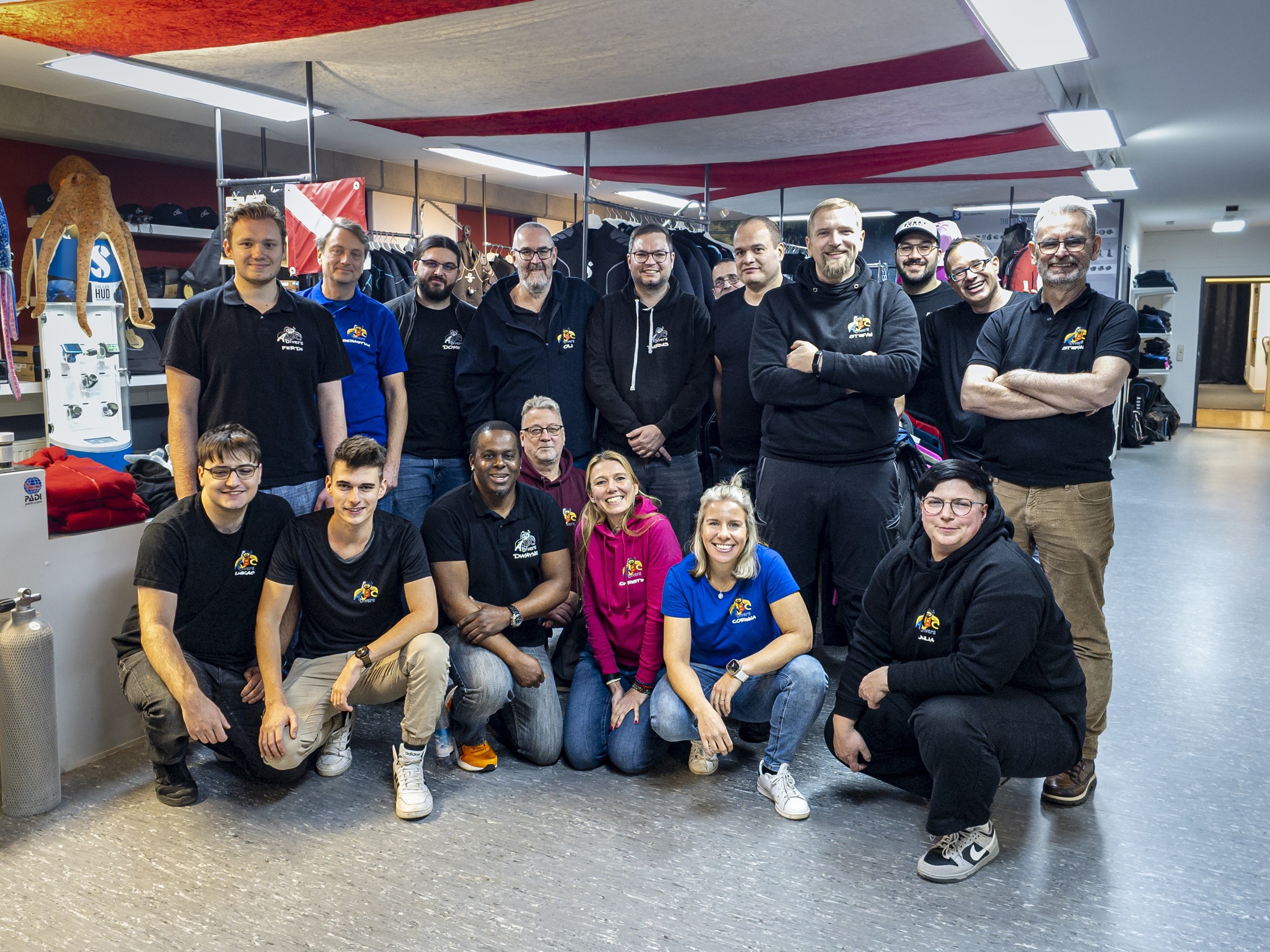 Staff photo of ABC Diving - about 20 smiling people stand in two rows