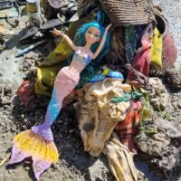 A mermaid doll atop a pile of debris removed from a lake in Switzerland