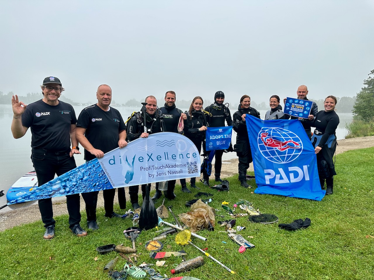 Cleanup divers from diveXellence pose with banners and the trash collected