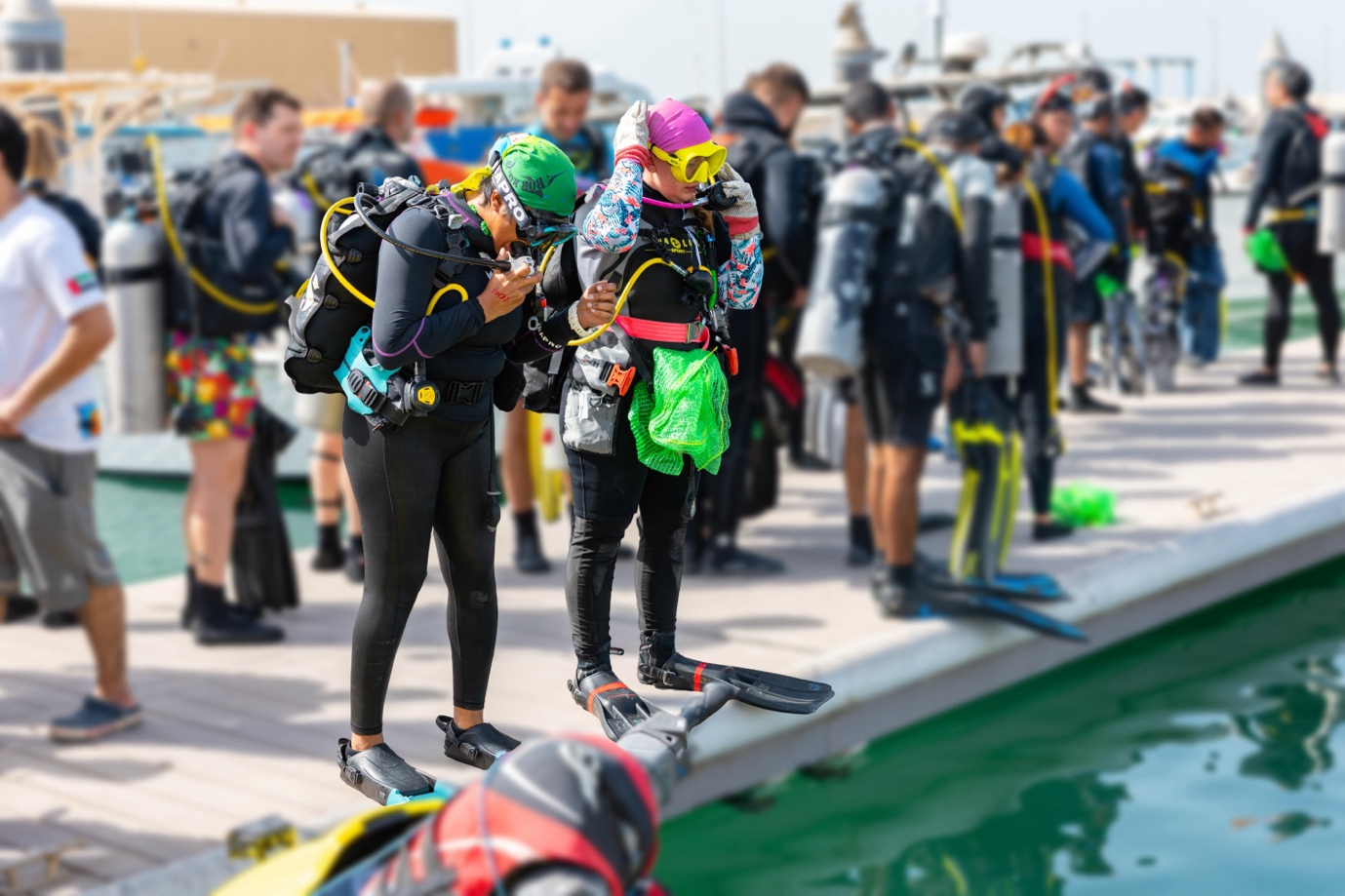 Two divers standing on a pier, geared up to go on an ocean cleanup