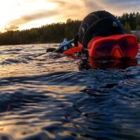 Elena Gushchina (lol2o) in a pink mask and a hood on the surface of a lake in Finland